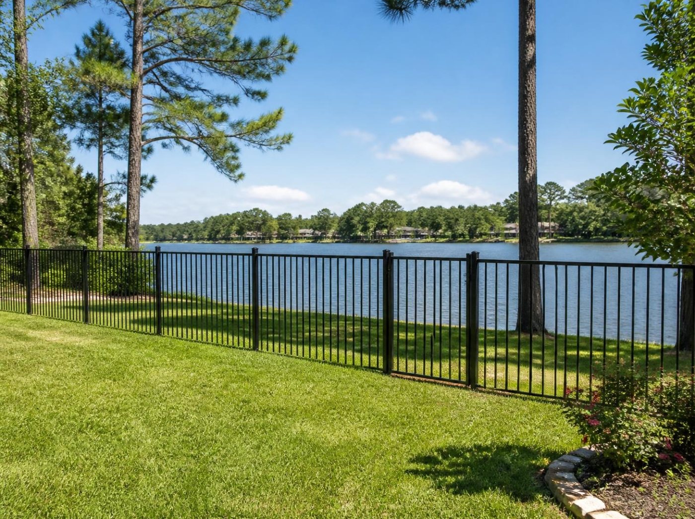 New black aluminum fence along a lakefront lawn